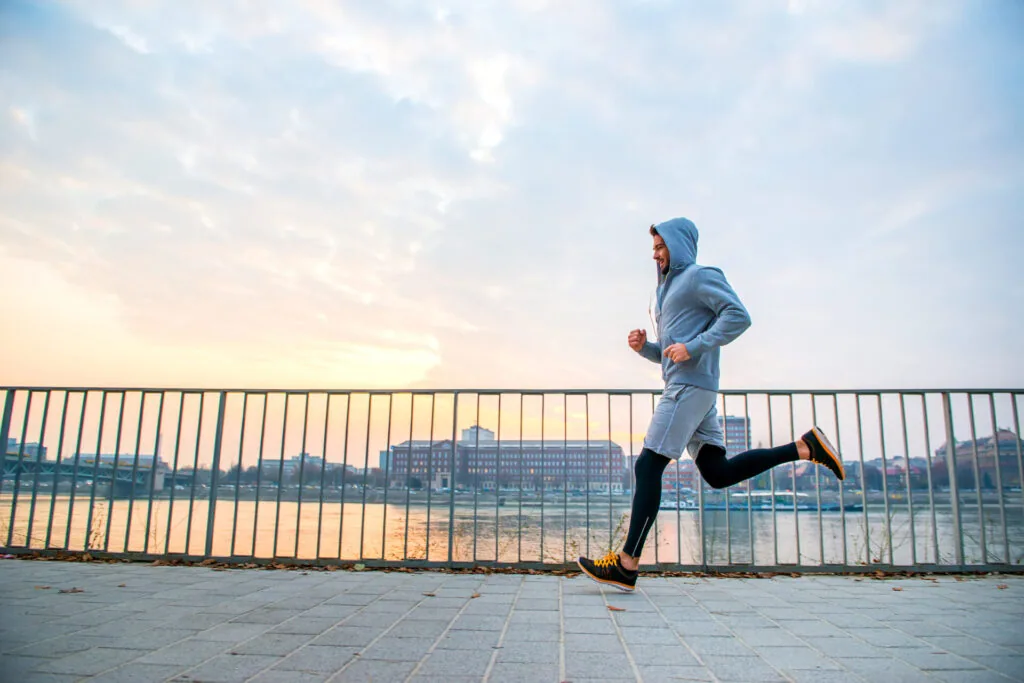 Person jogging on a bridge path overlooking a city waterfront and buildings